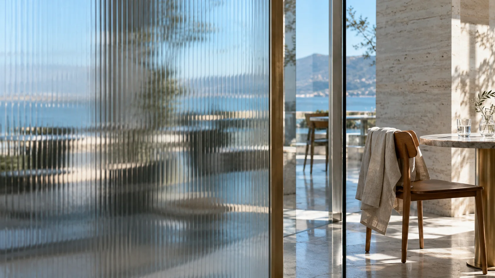 Ribbed glass obscuring most of a cafe, with one clear view of a table and a linen jacket